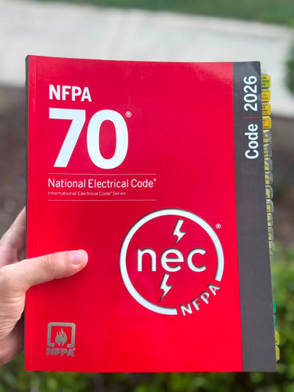 NEC 2026 codebook with handwritten exam notes from a Master Electrician